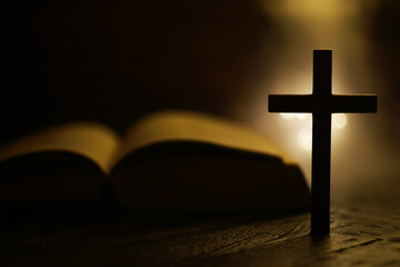Silhouette of Wooden Cross with Open Bible in Warm Candlelight