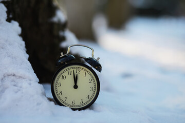 Vintage Alarm Clock on Snowy Ground Signifying Winter Time and Season Change