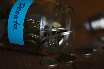 Spilled Donation Jar Filled with Coins on Wooden Surface
