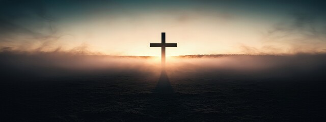Naklejka premium A cross is lit up in the fog at sunset
