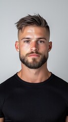 Fototapeta premium A man with a shaved head and a beard is wearing a black shirt