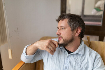 Pensive man sitting on sofa talking and gesturing with hand