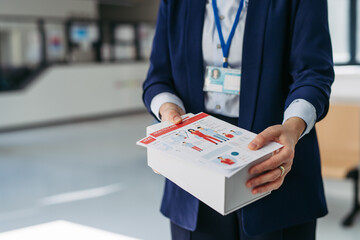 Close up of pharma rep holding box with samples of new medication and flyer.