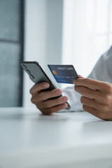 Man holding credit card and phone to pay online