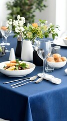Fototapeta premium Elegant table setting with a navy tablecloth, white and black ceramic tableware, fresh flowers, and a plated meal