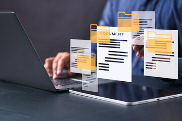 Businessman managing digital documents and folders on virtual interface, using laptop and tablet....