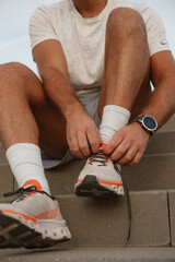 Close-up of a sportsman tying shoelaces on his running shoes, preparing for training session outdoors