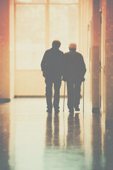 A church hallway after service with sunlight through windows A caregiver helps an elderly man walk with a steady pace It feels caring and respectful