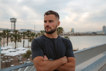 Portrait of a businessman posing with crossed arms in Barcelona, Spain, with beach and cityscape in background