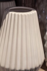 A pristine, ribbed ceramic vase with a wide opening, presented in a studio setting.