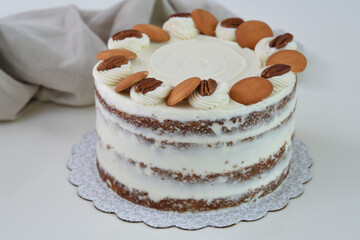 Delicious Carrot Cake with Nut Decorations spiced cake layers covered in smooth cream cheese frosting with napkin side view of classic and delicious cake
