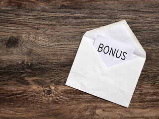 White envelope containing bonus notification on wooden table