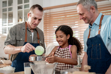 Caucasian senior gay couple baking bakery with adopted daughter in house. 