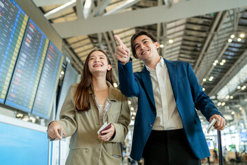 Asian businessman and woman walking in airport terminal to boarding gate. 