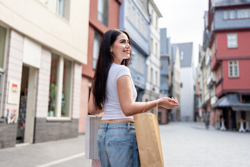 Fototapeta premium Mixed race woman hold shopping bags and walking at outdoor marketplace. 