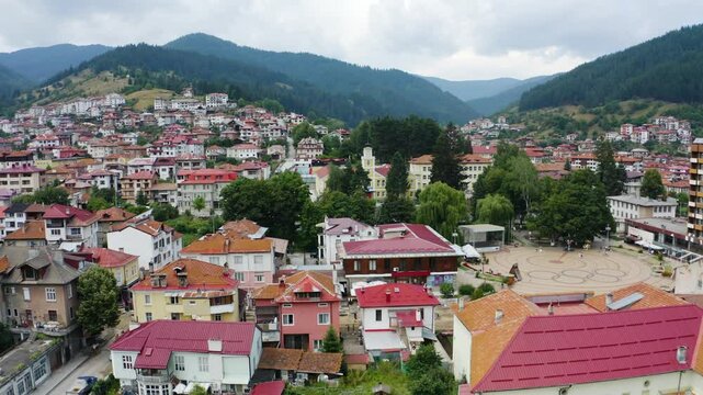 Establishing aerial footage of an old building with a clock tower in a small town in the mountain