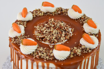 Carrot Cake with Cream Cheese Frosting and Drizzle caramel chocolate sauce with crushed nuts closeup side view of classic delicious cake