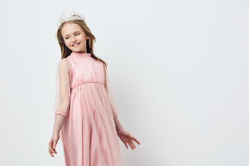 A joyful young girl in a light pink dress with sheer sleeves, smiling gracefully against a soft...