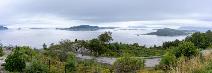 Panoramic view of the islands surrounding Alesund on Norway’s west coast, seen from Mount Aksla on a cloudy day, with lush greenery and calm coastal waters