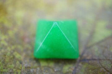 A green decorative pyramid on an autumn leaf.