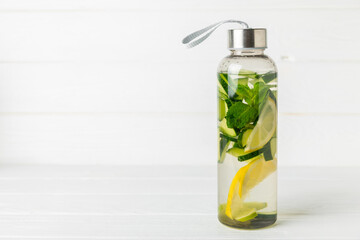 Cucumber water with lemon, lime and mint on a wooden table. Water infused with sliced...