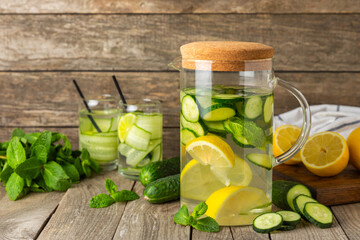 Cucumber water with lemon, lime and mint on a wooden table. Water infused with sliced...