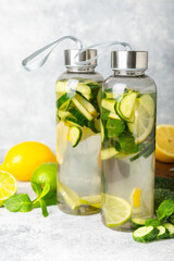 Cucumber water with lemon, lime and mint on a wooden table. Water infused with sliced ​​cucumber in a drinking glass. Tonic refreshing drink. Cucumber lemonade.Summer natural cooling drink.Copy space
