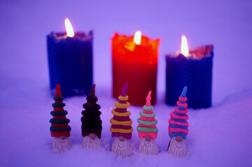 Colorful fairy-tale dwarfs made of plasticine on the background of burning candles.