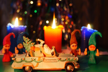 A toy car with Santa on the background of burning candles.
