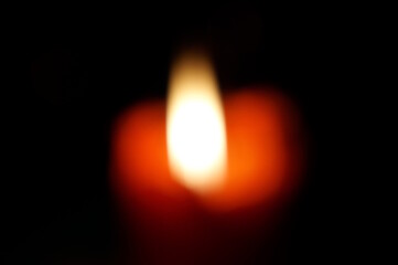 Blurred background. The flame of a burning candle on a dark background.