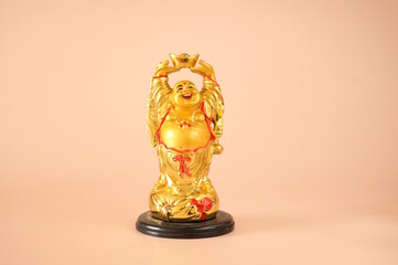A statue of a smiling Buddha on a pink background.