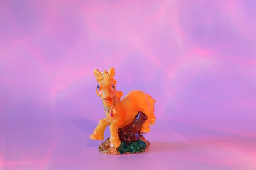 A horse figurine on a pink rainbow background.