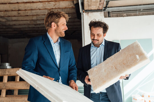 Two men in business attire discussing energy efficiency at a construction site