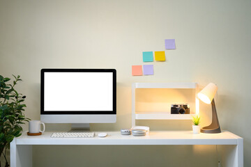 Modern workspace with desktop monitor, sticky notes on wall, desk lamp, and creative decor