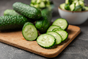 Cucumber on wooden background. Slice of cucumber on background. Fresh organic green cucumbers gherkin. Vegan. Salad ingredient. Farm vegetables. Cut vegetables with knife. Space for text. Copy space
