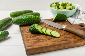 Cucumber on wooden background. Slice of cucumber on background. Fresh organic green cucumbers gherkin. Vegan. Salad ingredient. Farm vegetables. Cut vegetables with knife. Space for text. Copy space