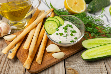 Cucumber sour cream tzatziki sauce on a wooden table.Tartar sauce. Traditional delicious appetizer. yogurt sauce. Tzatziki with ingredients cucumber, garlic,dill,lemon,mint. salad dressing.Copy space