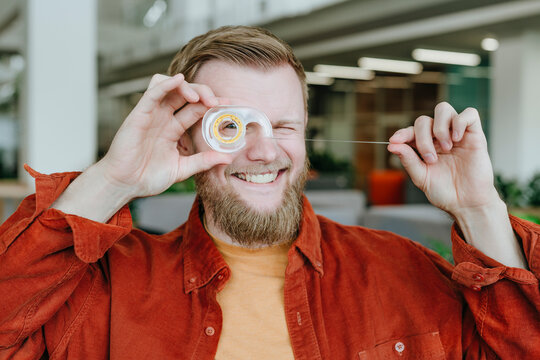 Businessman having fun with a scotch tape dispenser in a modern office