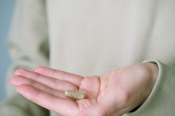 Close up hands showing with one herbal capsules. Home alternative remedy for pain, opioid addiction, dangerous painkiller. Health concept. top view