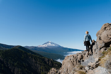 Fototapeta premium Tourist standing on mountain admiring breathtaking view of volcano Teide, Tenerife, Canary, Spain.