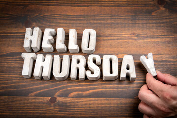 Hello Thursday. Concrete alphabet letters and coffee mug on dark wooden texture background