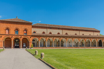 Ferrara, Italy - May 17, 2025: Experience the stunning architectural beauty of the Charterhouse of Ferrara, Italy, showcasing its elegant arches and serene garden views under a bright blue sky