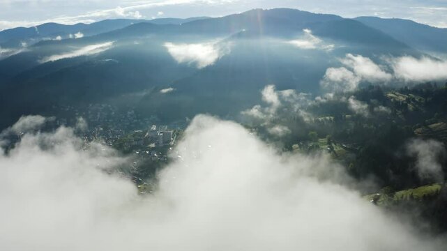 Aerial reveal of a small town in the mountains with clouds