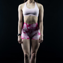 Athletic woman showing sculpted abs and toned physique posing on black background
