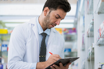 Fototapeta premium Pharmacist checking stock of drug on shelves with digital tablet in the pharmacy drugstore