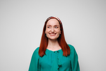 Smiling redhead woman in summer outfit standing isolated on grey