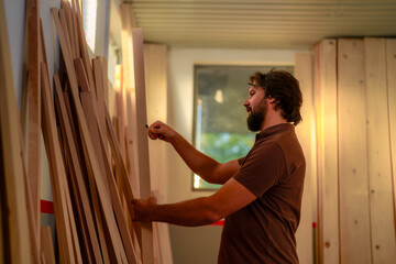 Carpenter is carefully measuring wooden planks in his workshop, meticulously preparing for a...