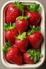 Top view of fresh strawberries in takeaway packaging, strong key lighting, product shot for ecommerce.