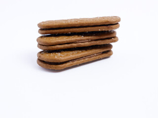 Stack of chocolate cream sandwich biscuits on a white background, sweet and crunchy with visible sugar crystals