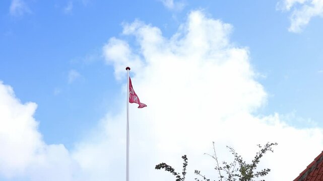 Denmark flag with letters waving in the wind with a background of a blue sky with clouds